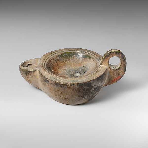 A small ancient Roman terracotta oil lamp with a rounded bowl, a short spout, and a loop handle.