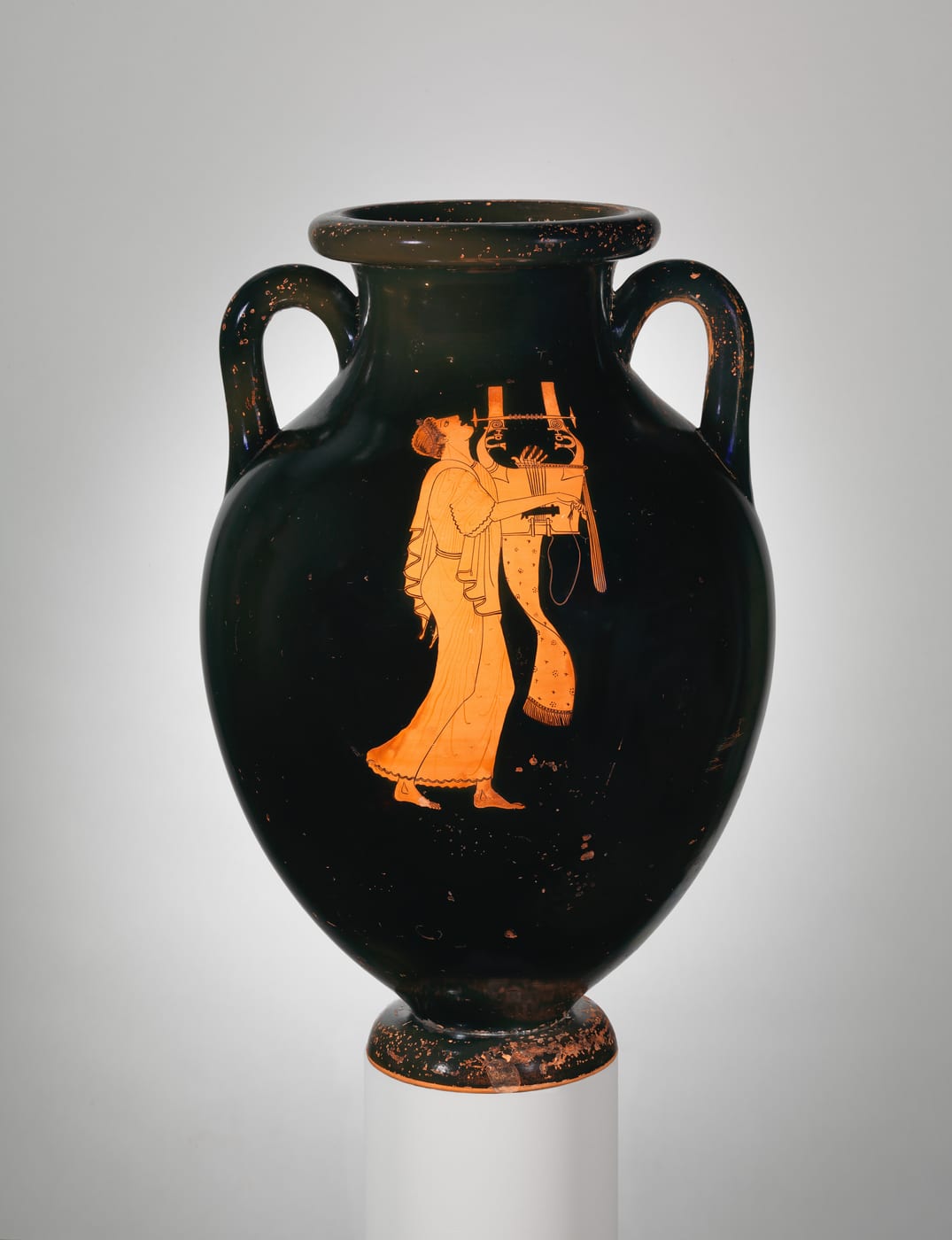 A Greek terracotta amphora painted with a standing figure holding a lyre.
