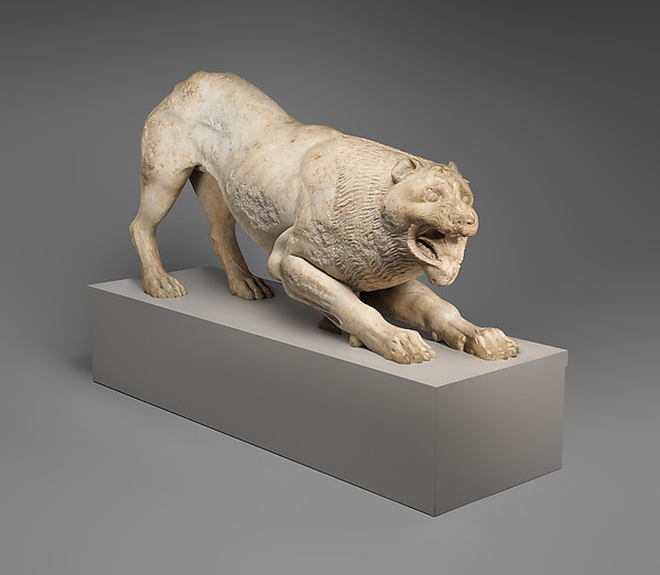 A Greek marble lion statue lying down with its head raised.