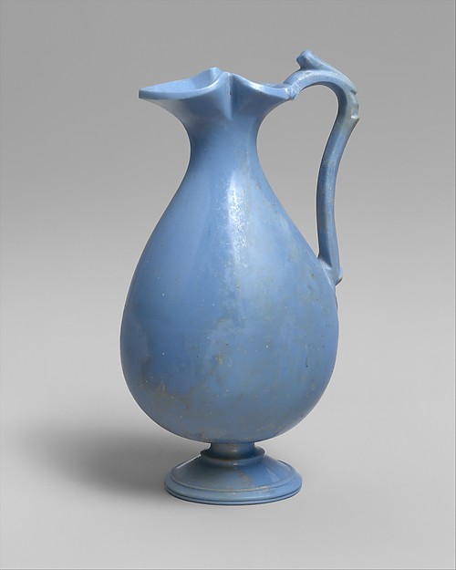 A Roman glass jug with a rounded body, narrow neck, handle, and small pouring mouth.